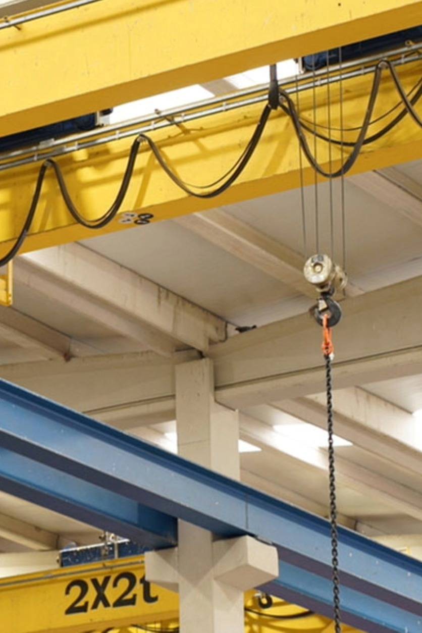 Mantenimiento de útiles de elevación y puentes grúa Puente grúa industrial en funcionamiento dentro de nave equipada con sistemas de elevación seguros