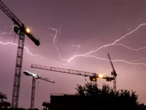 Rayos ramificados sobre grúas torre en una obra de construcción, destacando el riesgo para trabajadores en altura.